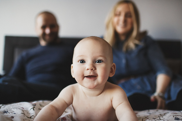 a family lifestyle photoshoot baby on bed parents in background hollygoeslightly